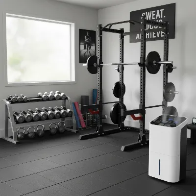 A clean, organized garage gym with a modern dehumidifier actively running in the corner, bright and well-lit with fitness equipment prominently displayed.
